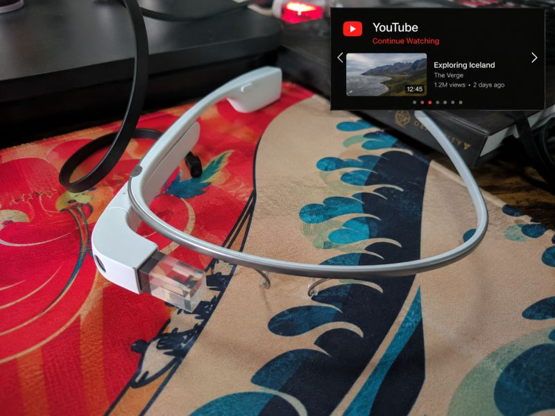 Google Glass Explorer Edition on a desk showing a YouTube card on its display